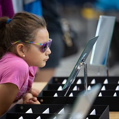 young girl trying on glasses at vision clinic